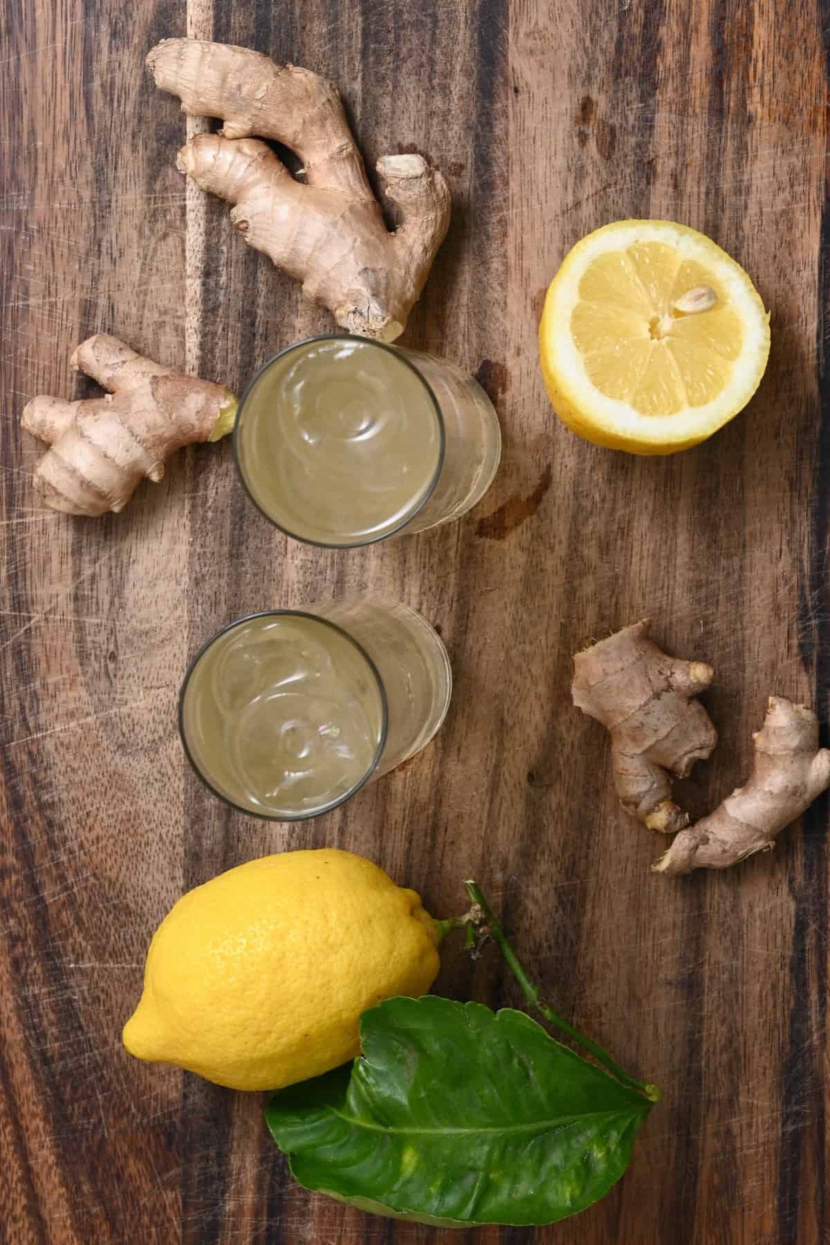 Two glasses with ginger ale and ginger and lemon around them