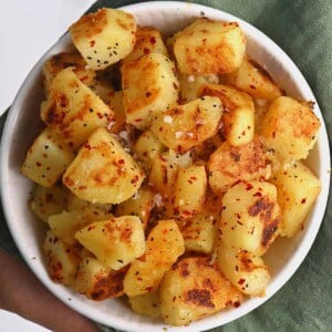 Home fries topped with salt and paprika in a bowl
