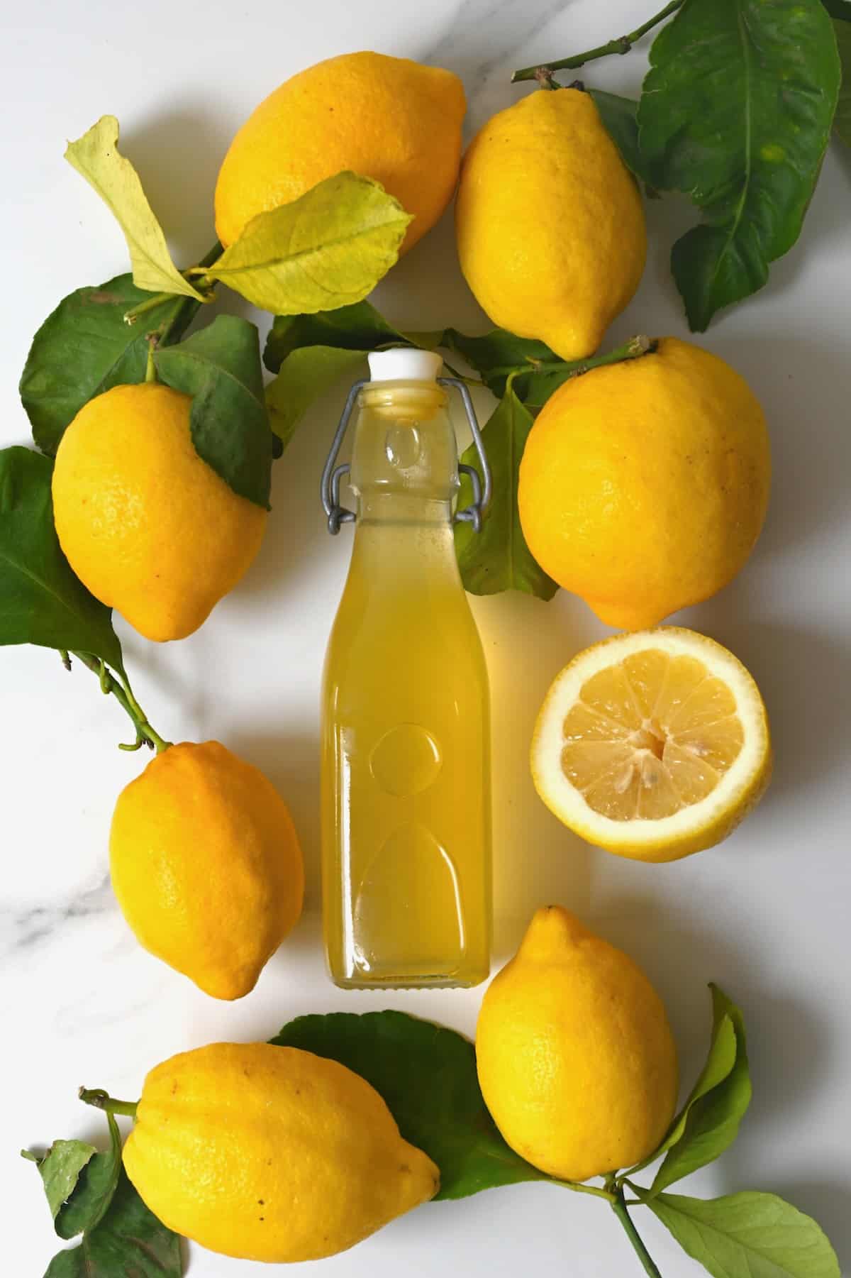 Lemon syrup in a bottle and seven and a half lemons around it