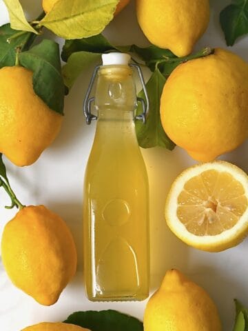 Lemon syrup in a bottle and lemons around it