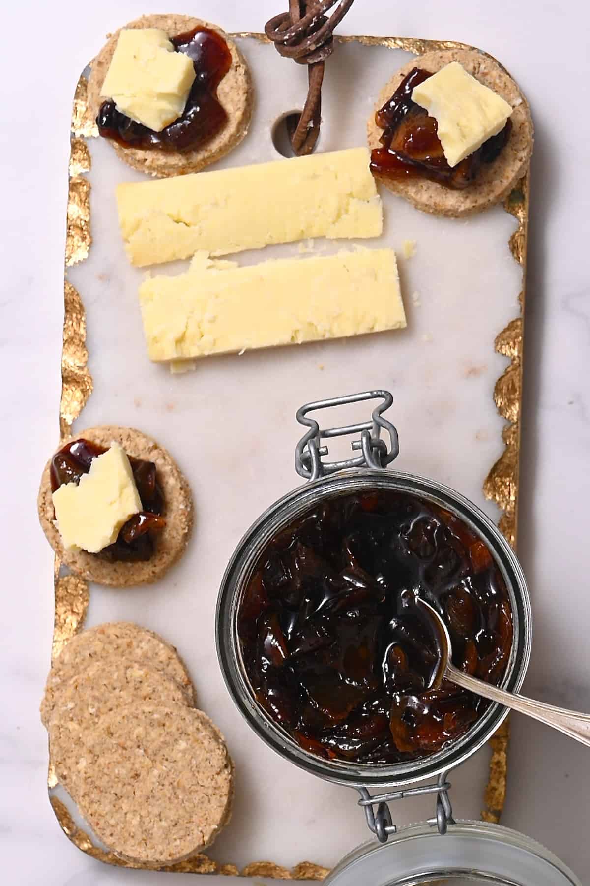 Onion jam in a jar and crackers and cheese next to it