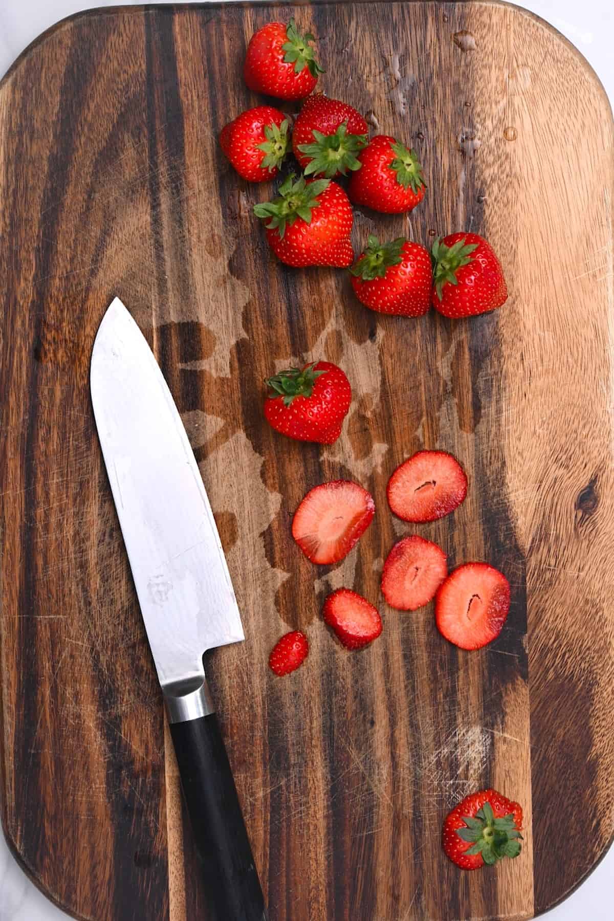 A knife and thinly sliced strawberries