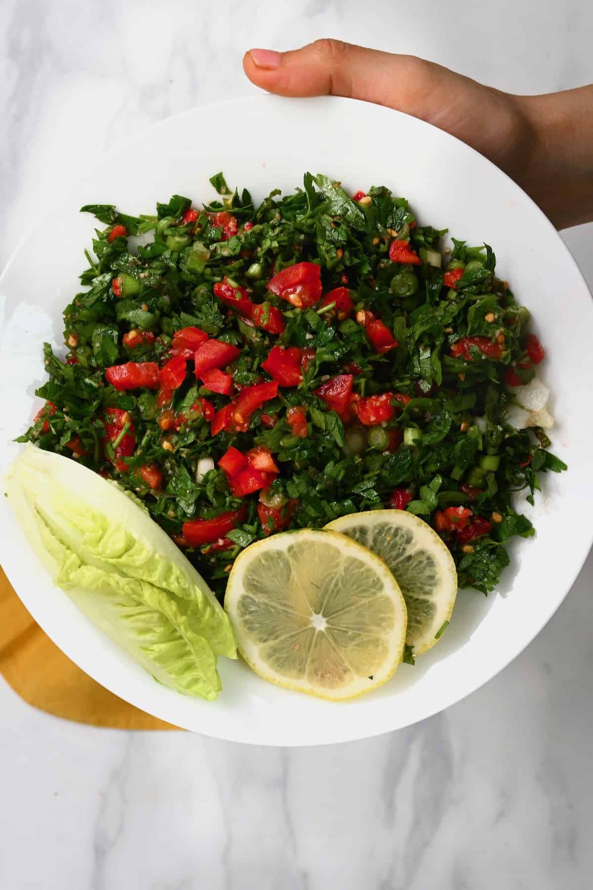 A serving of tabbouleh salad with slices of lemon
