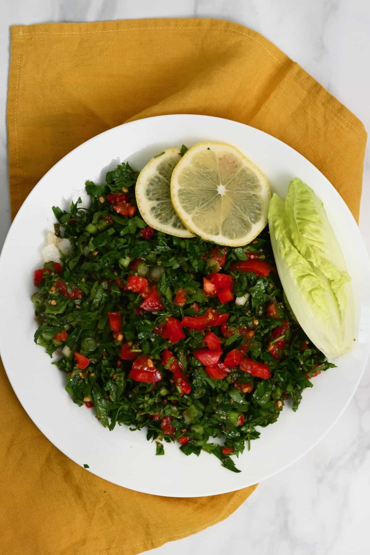 Tabbouleh served on a plate with lemon slices and lettuce
