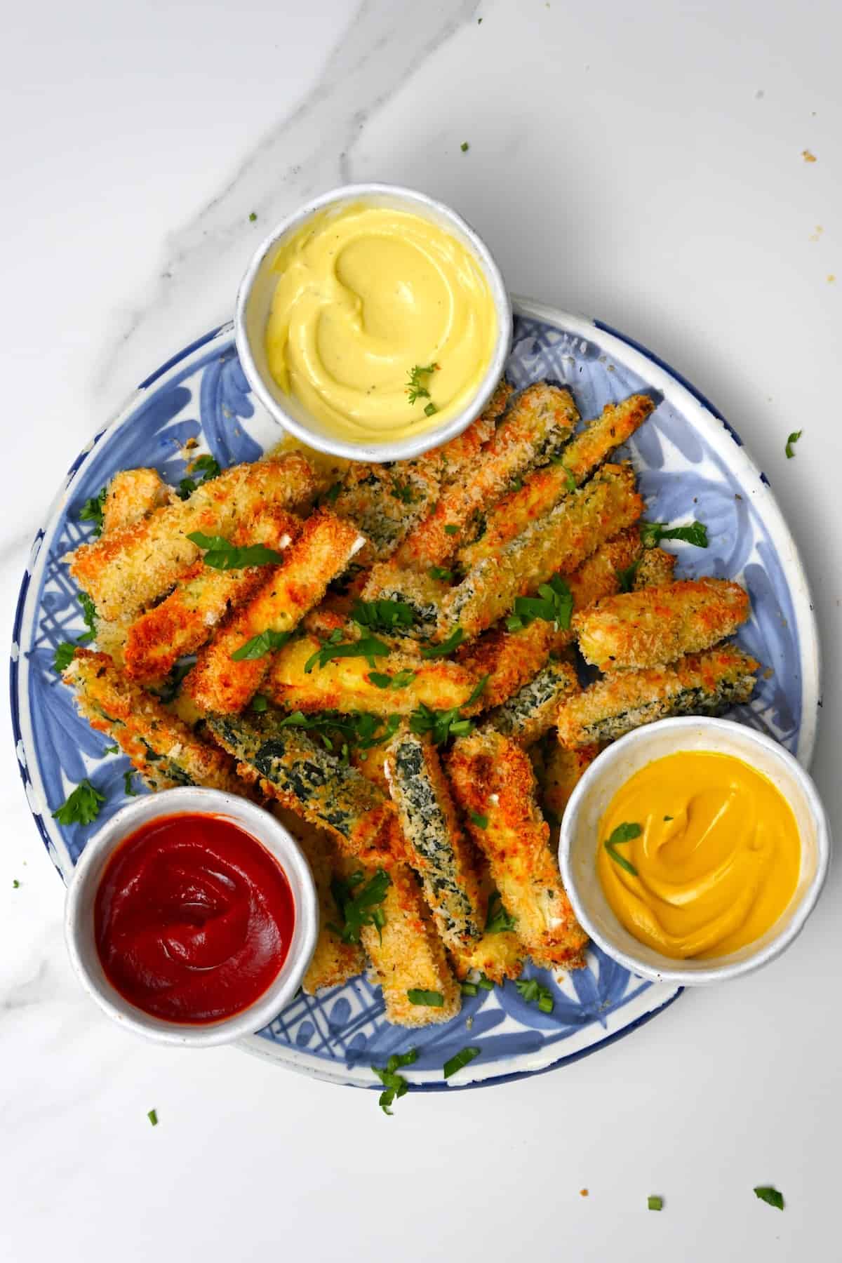 A plate with zucchini fries and three dips in little bowls