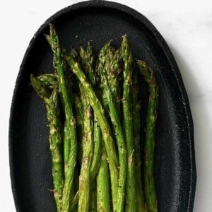 Air fried asparagus on a black plate