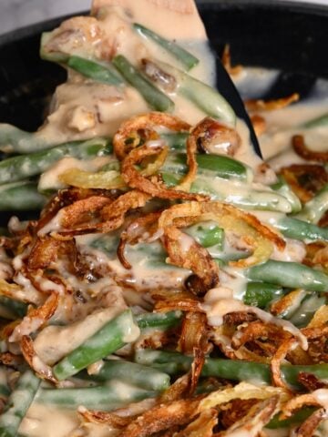 A spoonful of green bean casserole topped with crunchy onions