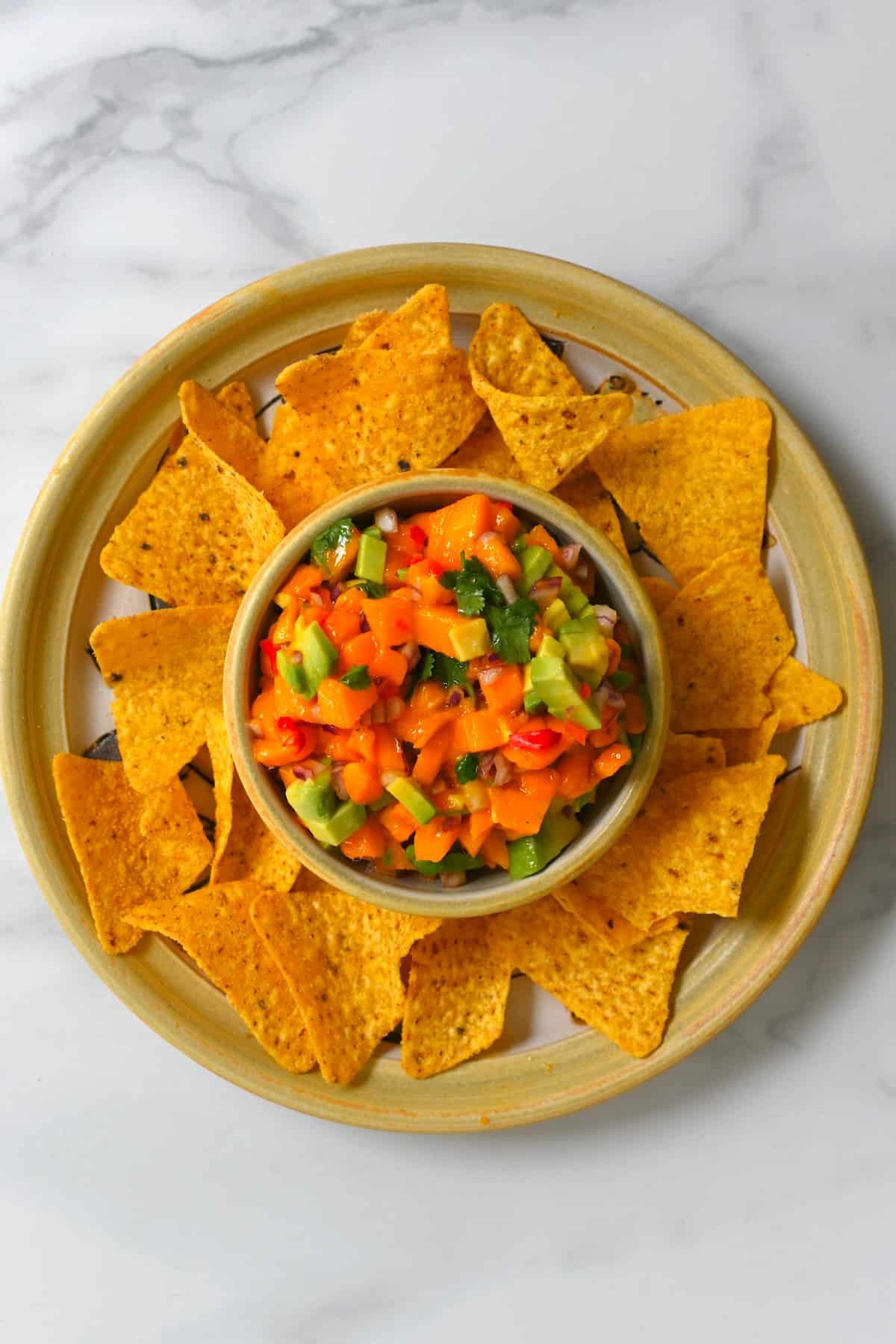 A bowl with chips and a bowl with mango avocado salsa