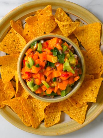 A bowl with chips and a bowl with mango avocado salsa