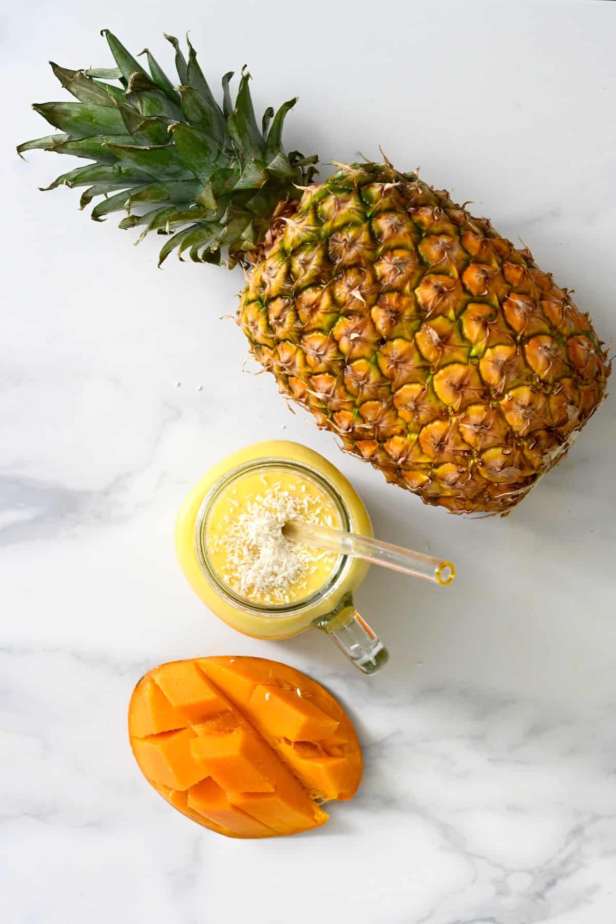 A pineapple, yellow smoothie, and half a mango