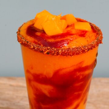 A glass with mangonada topped with mango cubes