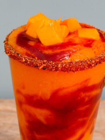 A glass with mangonada topped with mango cubes