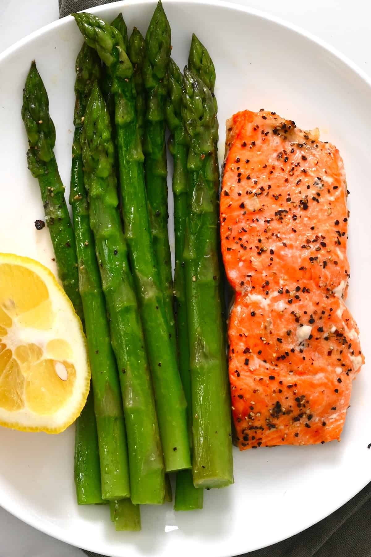 A serving of salmon and asparagus with lemon slice