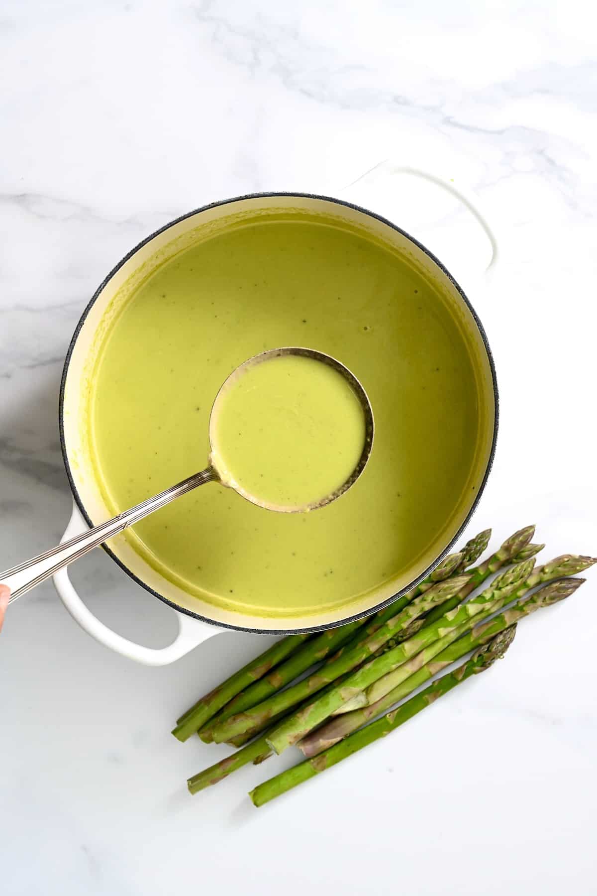 A pot and ladle full with asparagus soup