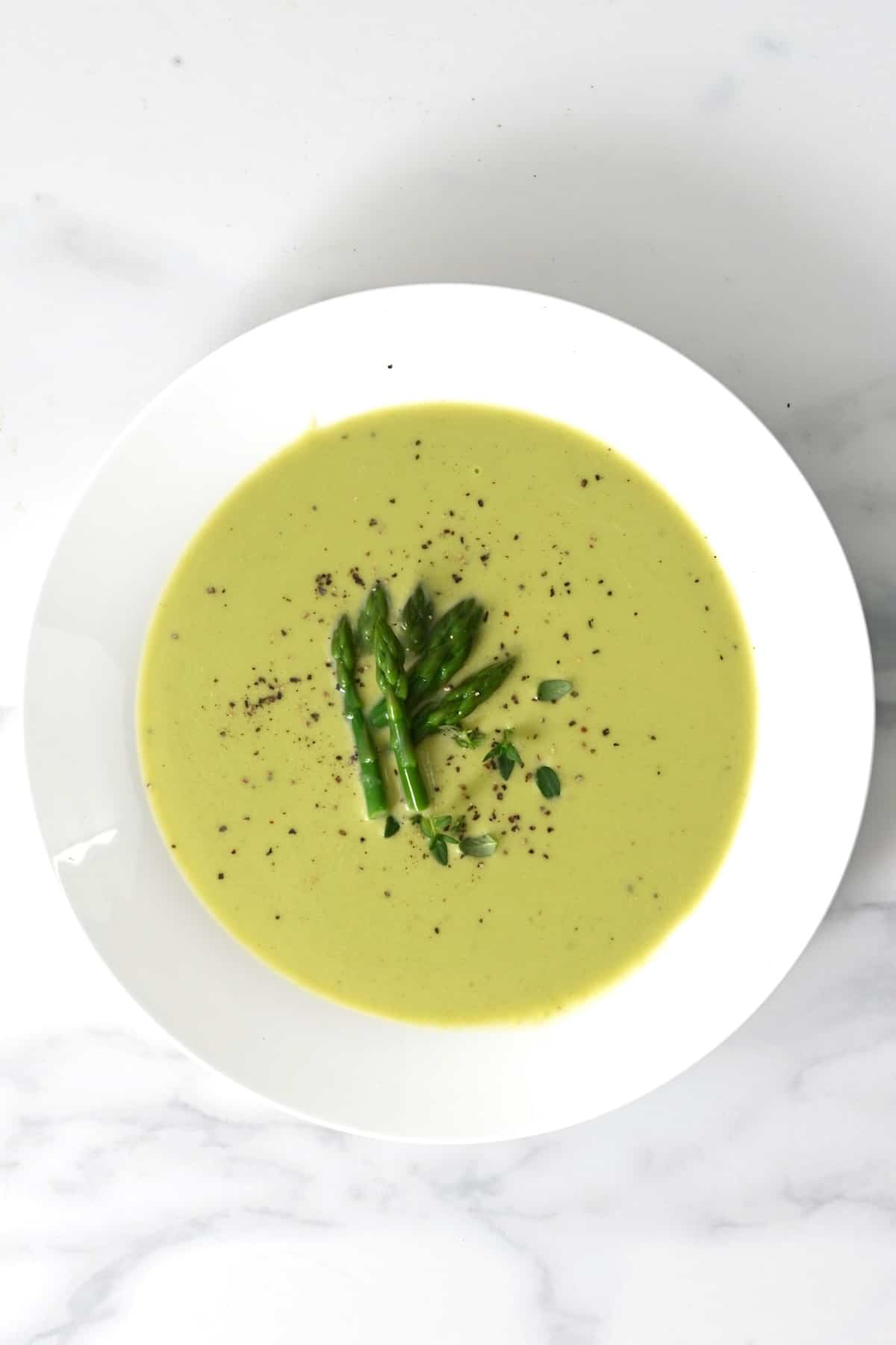 A bowl with asparagus soup topped with asparagus tips