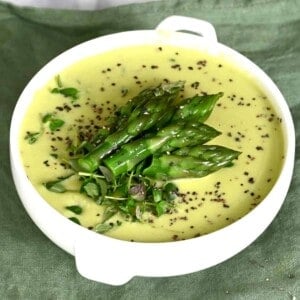 A small bowl with asparagus soup topped with asparagus tips