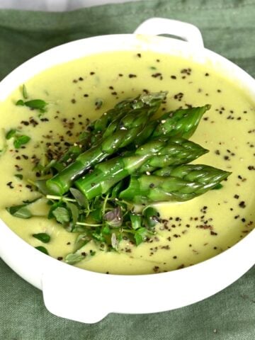 A small bowl with asparagus soup topped with asparagus tips
