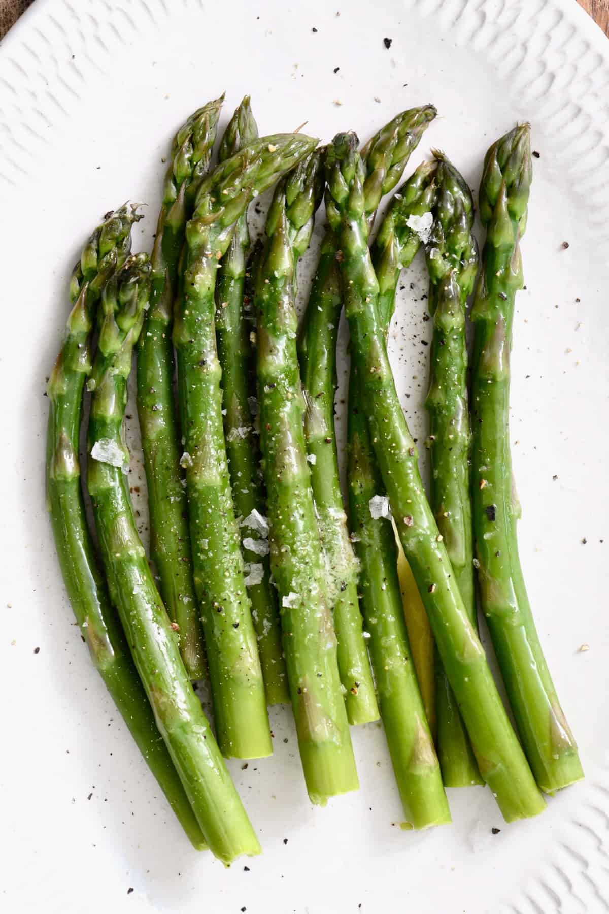 Cooked asparagus topped with salt on a plate