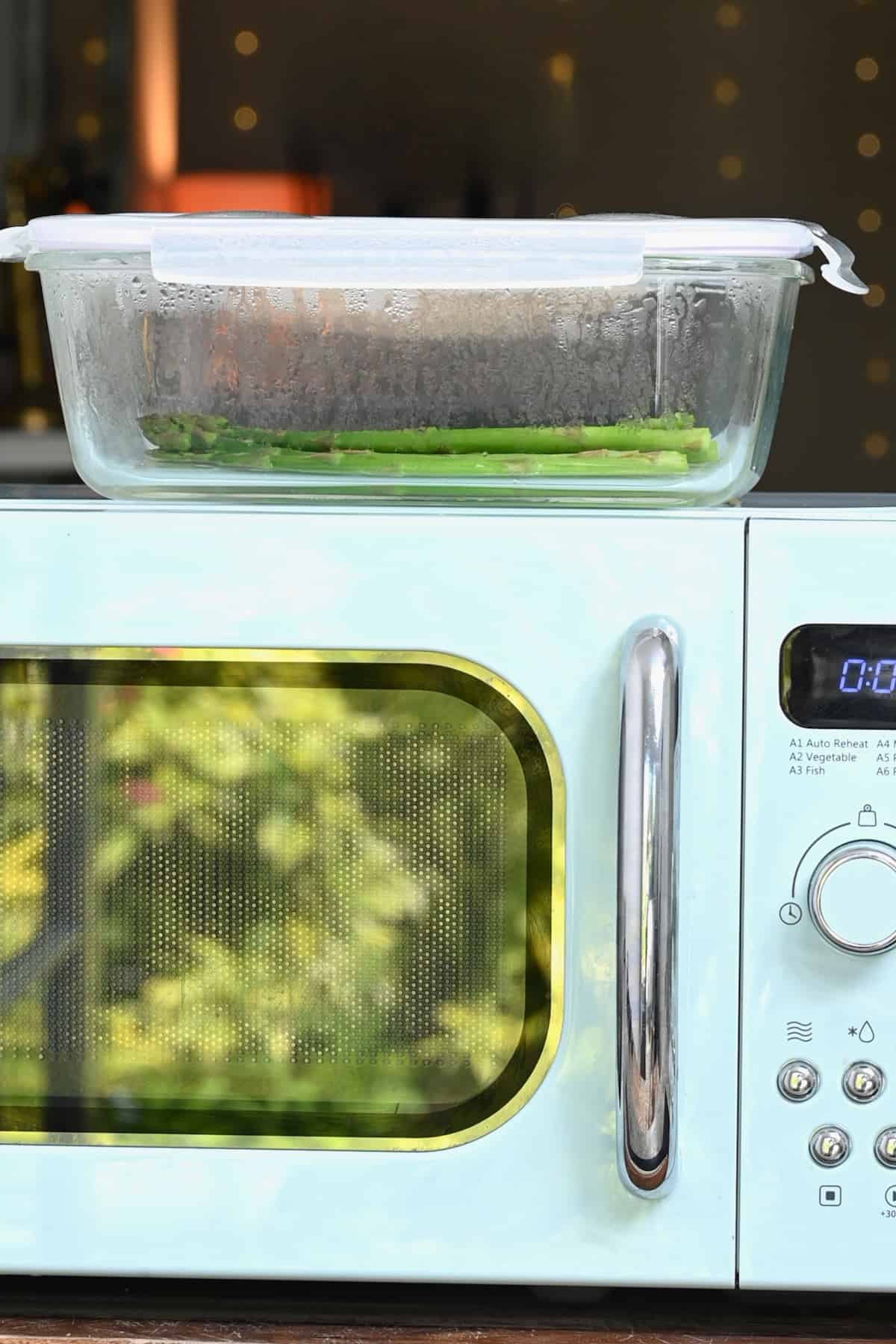 Steamed asparagus on top of a microwave