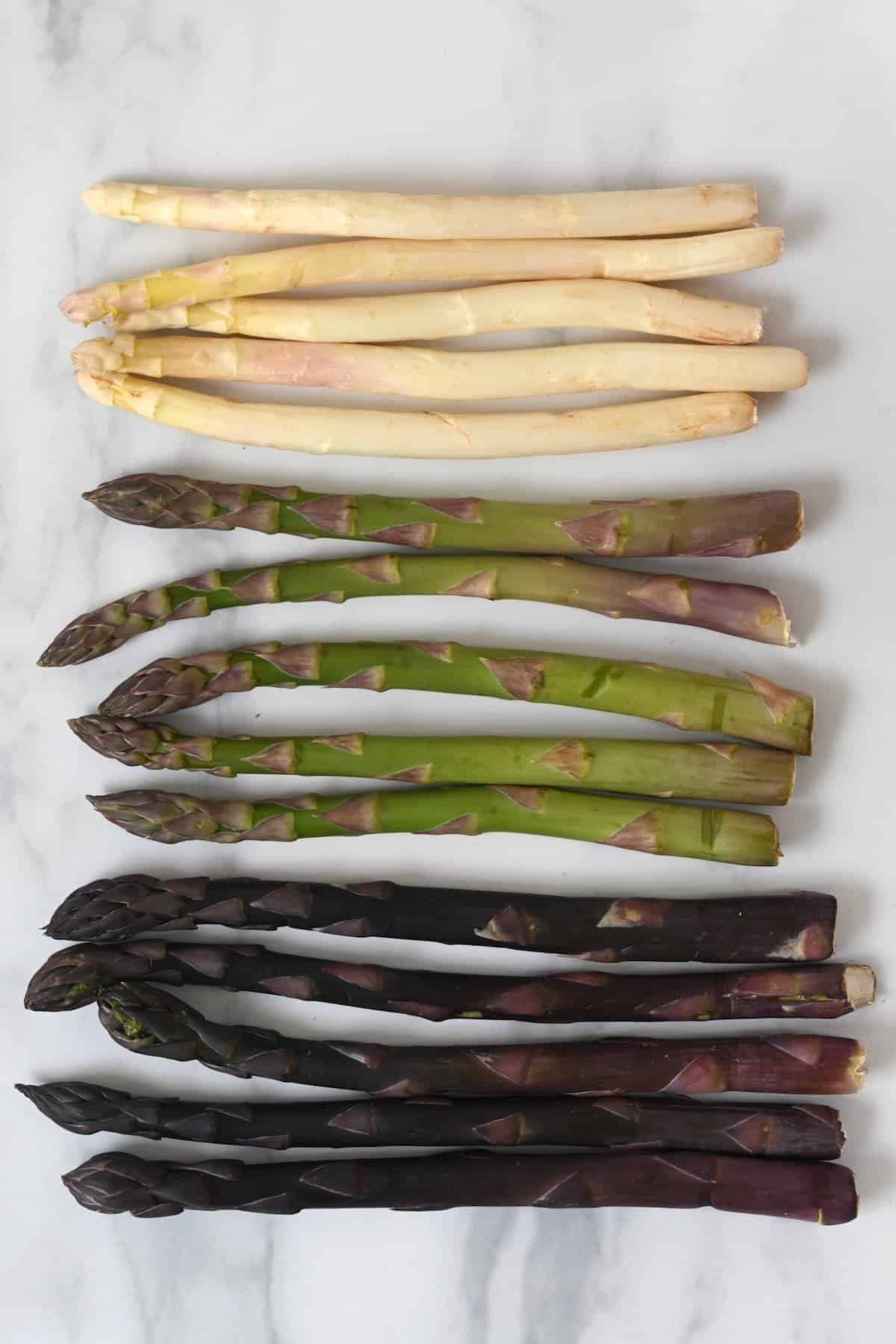 White, green and purple asparagus on a flat surface