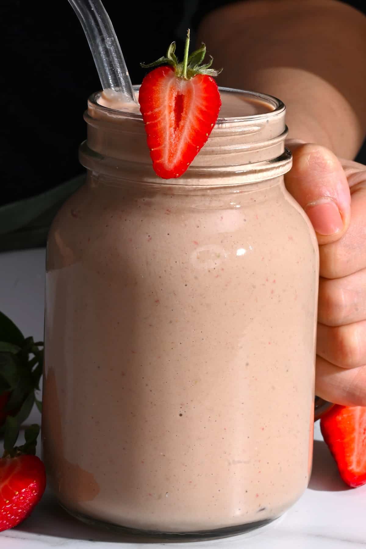 A large mason jar with breakfast smoothie topped with strawberry