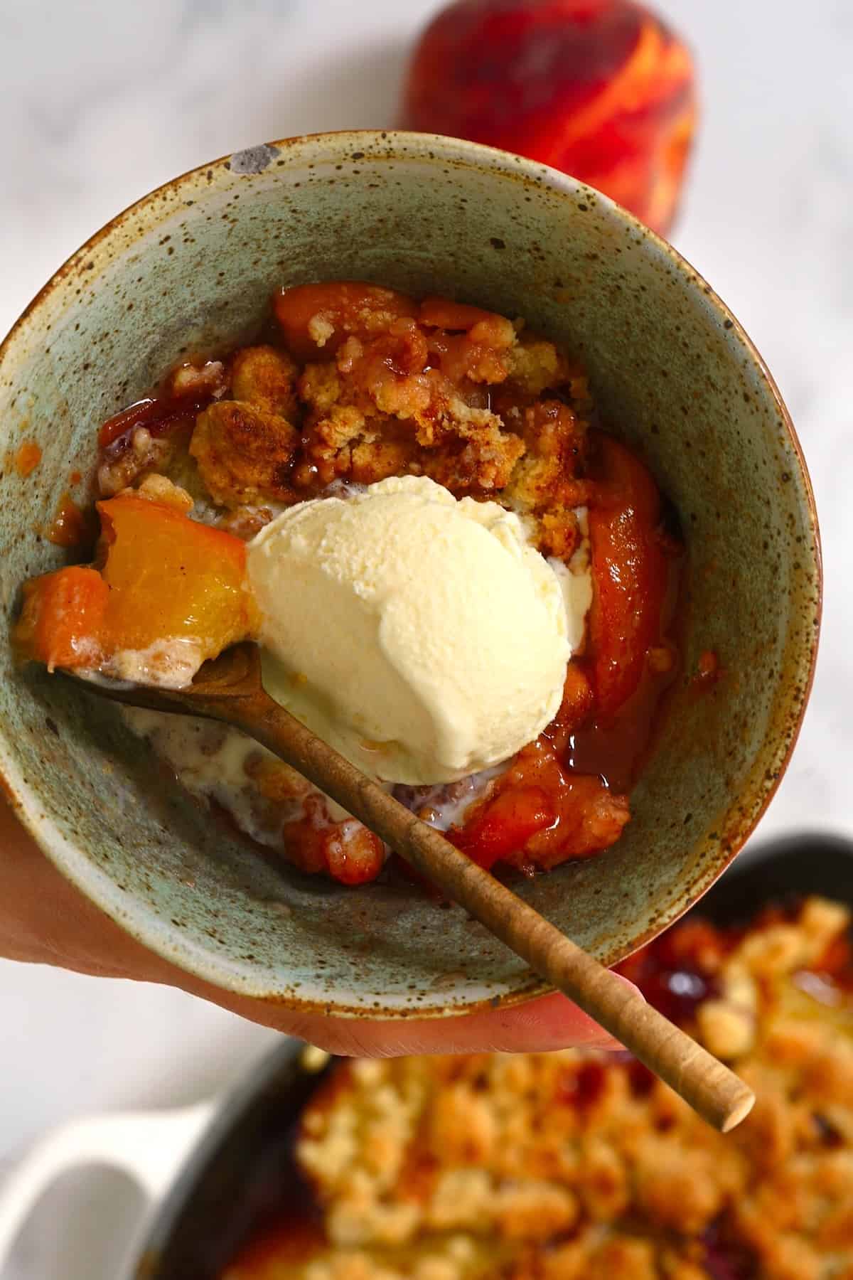 A serving of peach crumble with ice cream on top