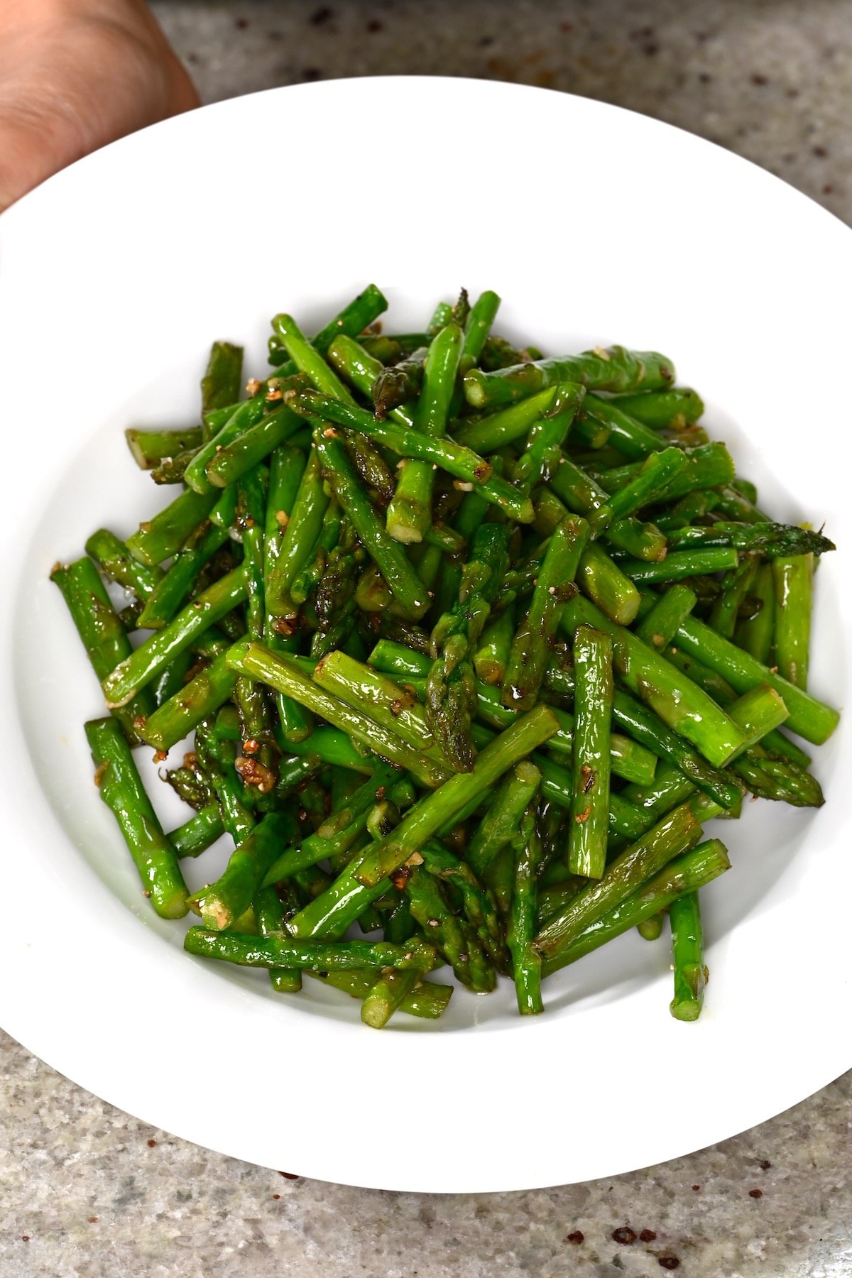 A serving of sautéed asparagus in a white plate