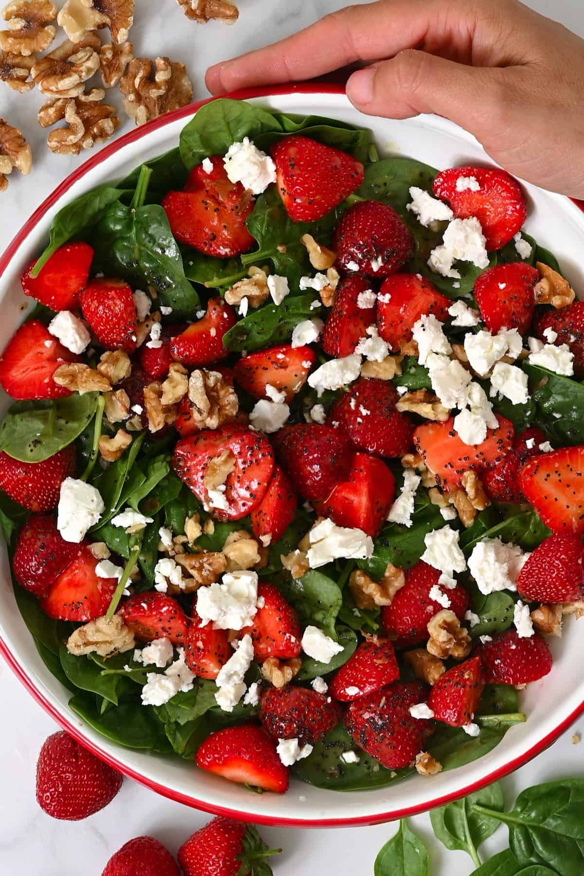 A bowl with strawberry spinach salad and feta cheese