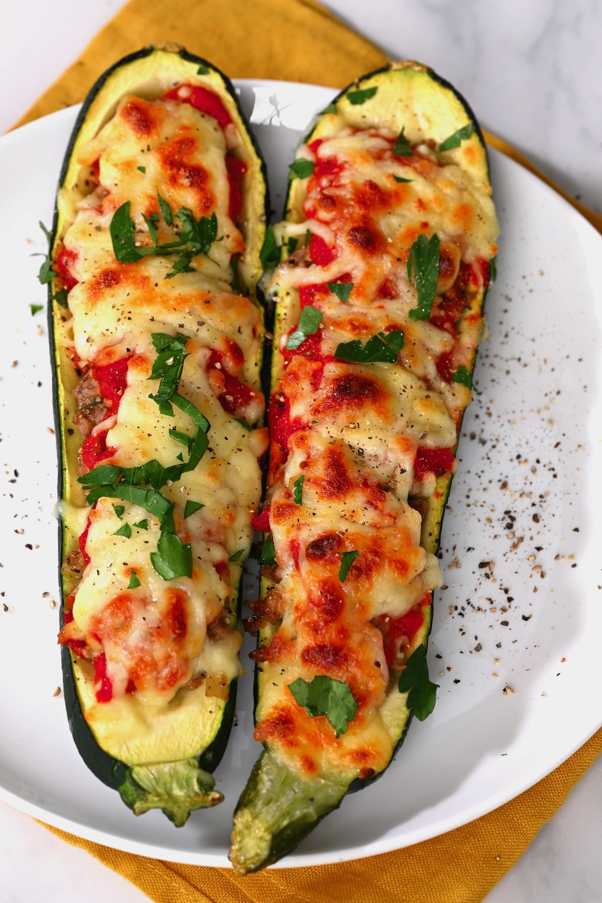 Two halves of stuffed zucchini topped with cheese and parsley