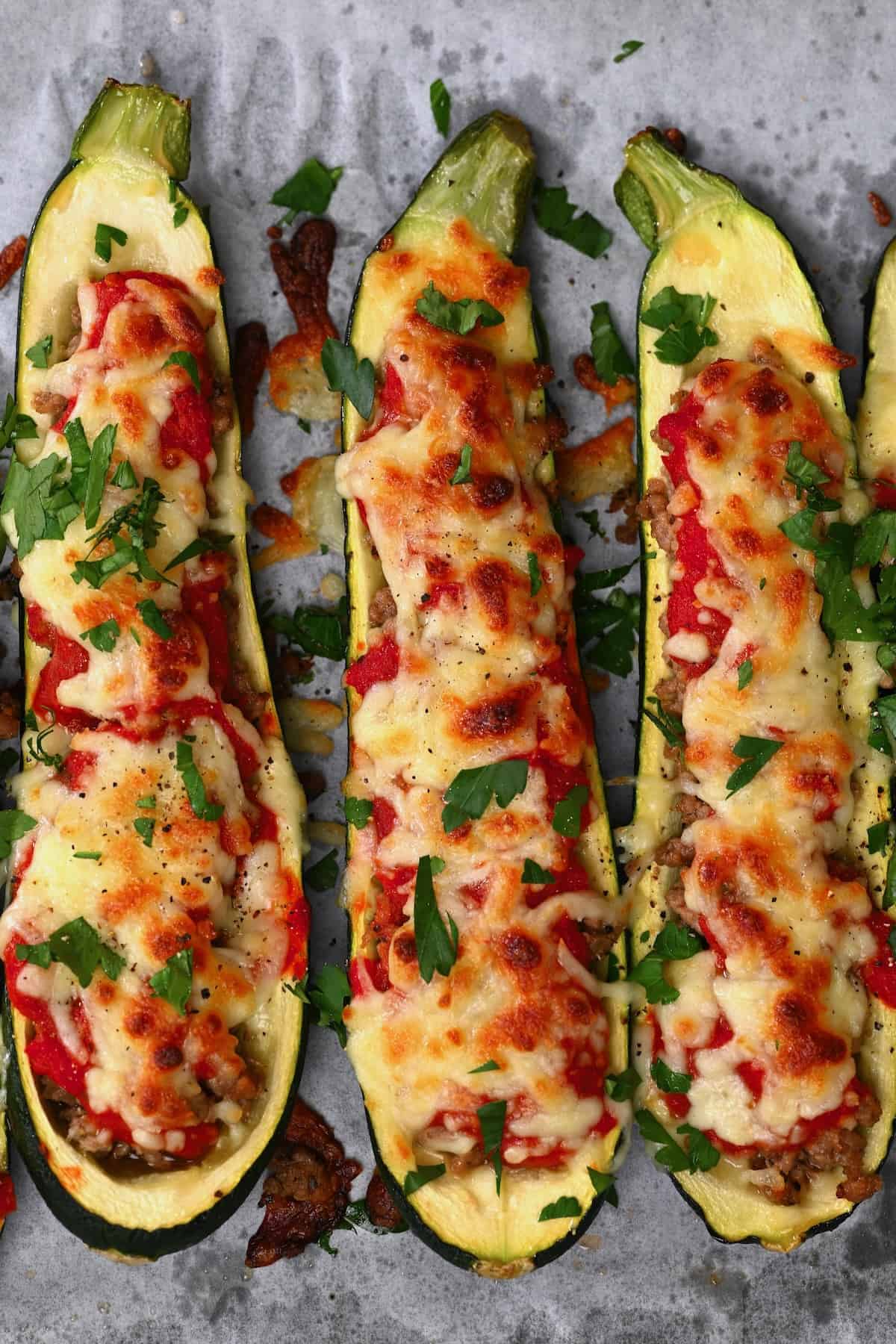 Three halves of stuffed zucchini topped with cheese and parsley