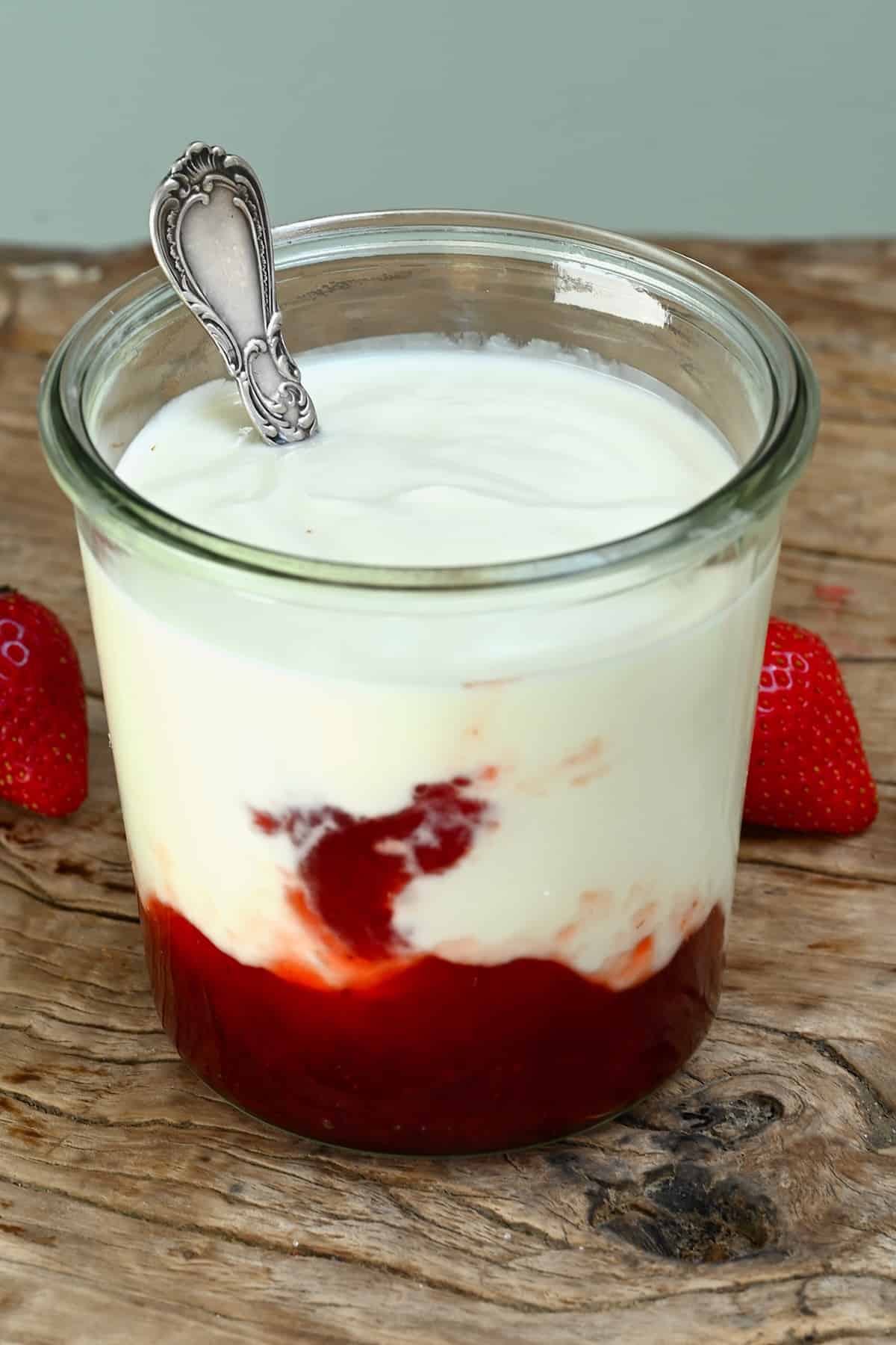 A jar with homemade coconut yogurt and strawberry syrup