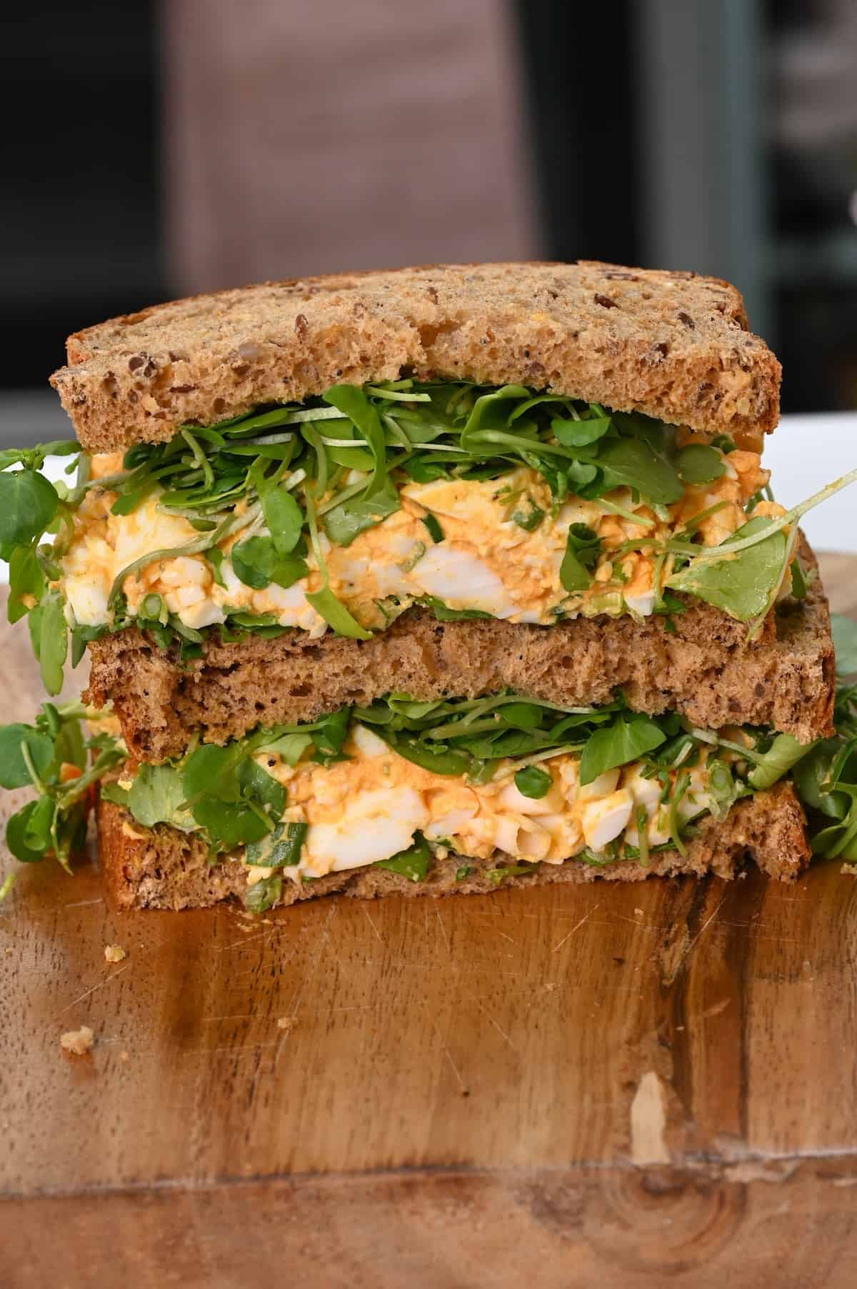 Egg salad sandwich cut in two on a board