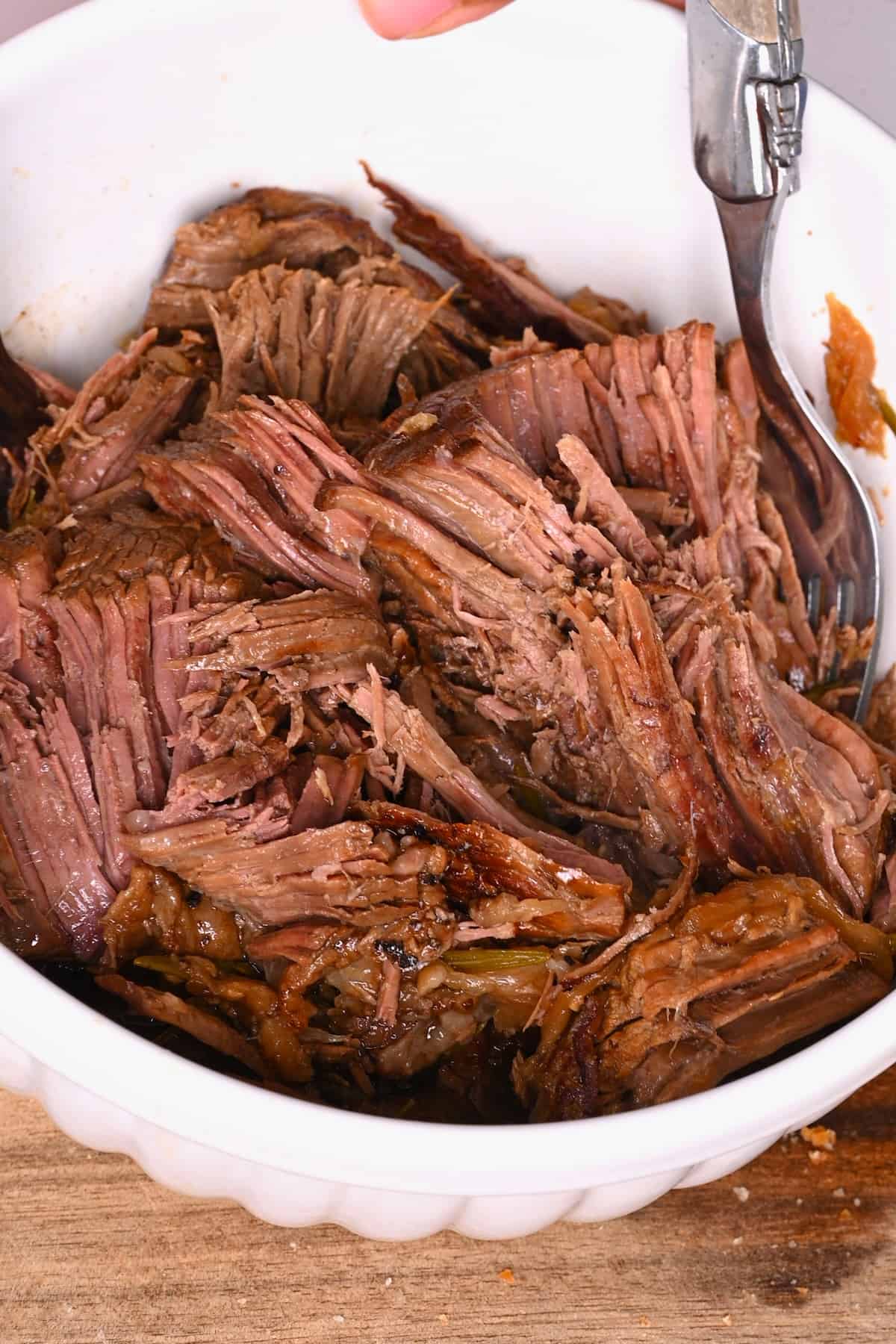 Slow cooked beef being shredded into pieces