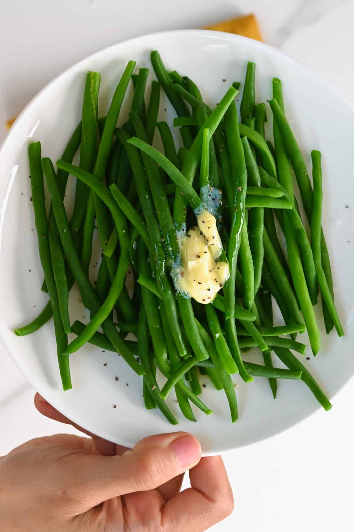 Boiled green beans topped with butter salt and pepper