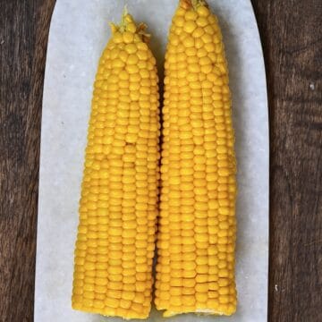 Two microwaved ears of corn on a plate