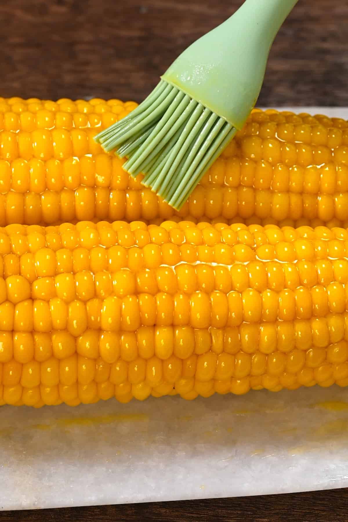 Brushing melted butter on corn