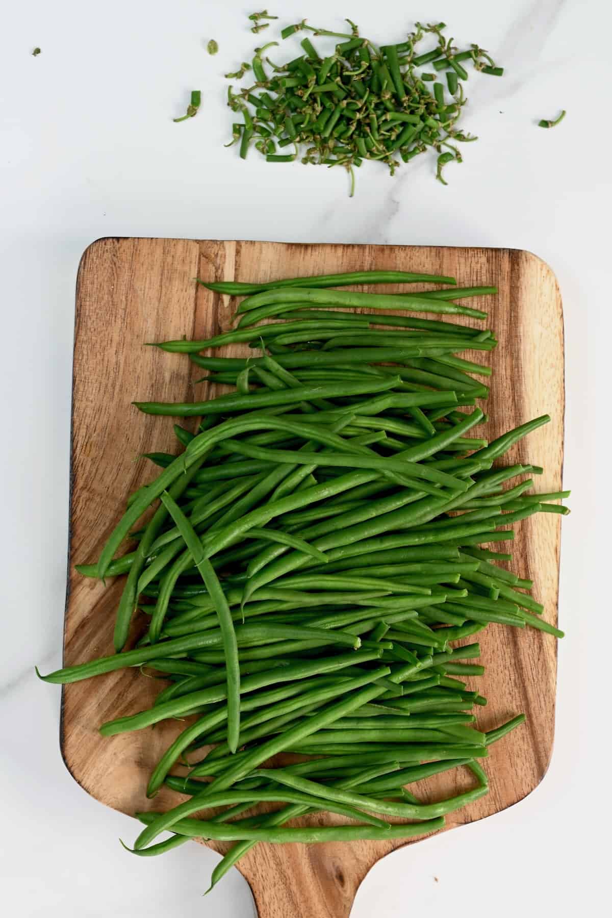 Green beans with trimmed eds on a chopping board