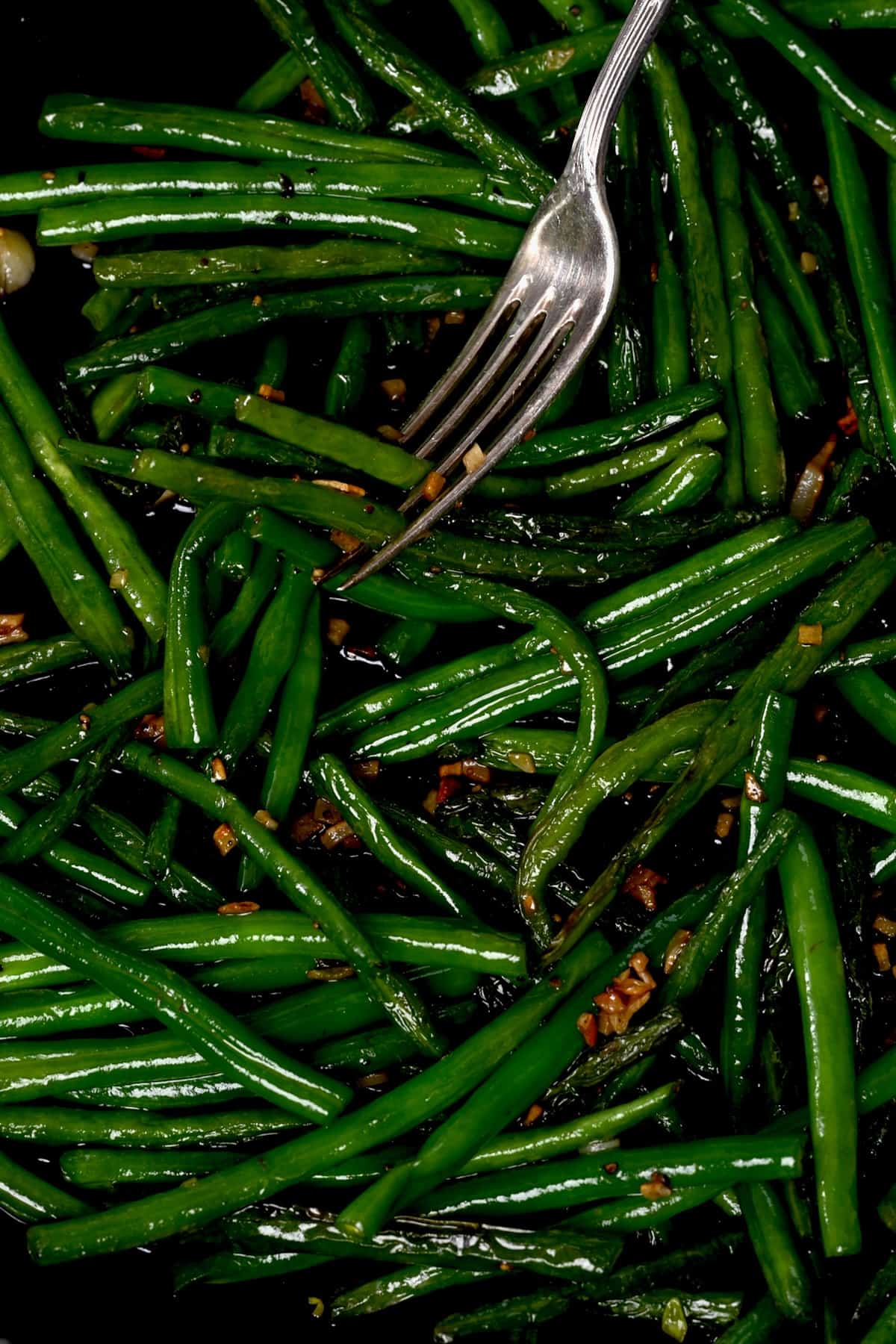 A forkful of green beans cooked in a pan