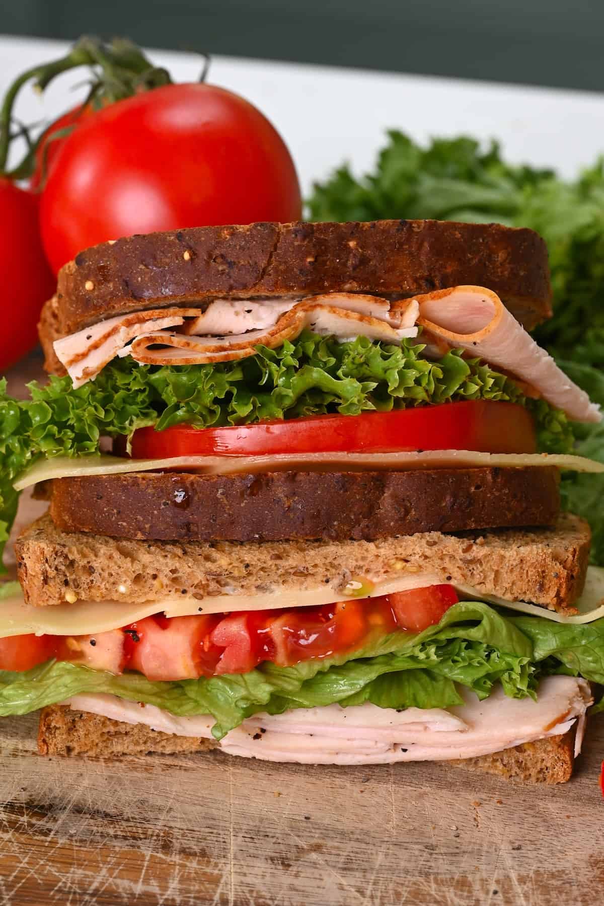 A close up of a turkey sandwich to tomato and lettuce