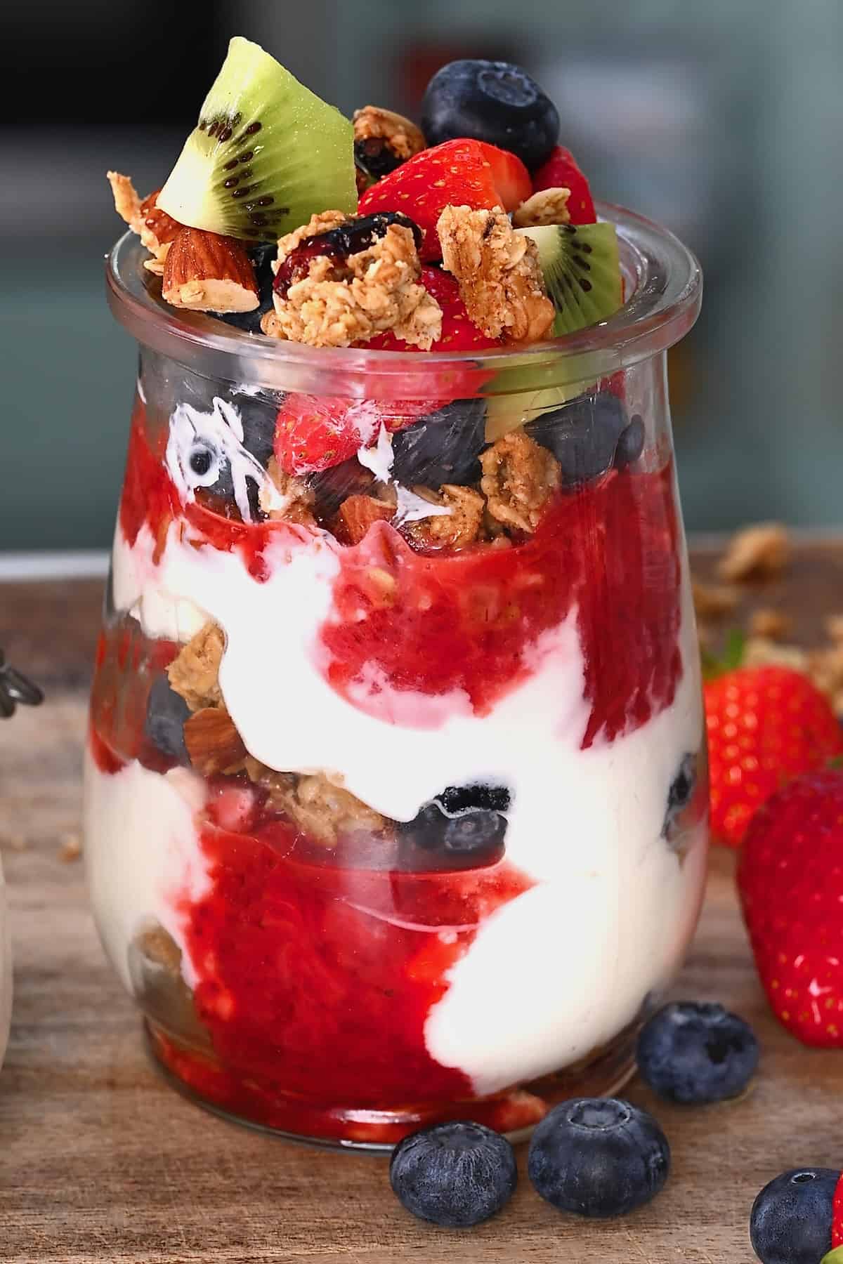 A small glass cup with yogurt parfait topped with berries and kiwi
