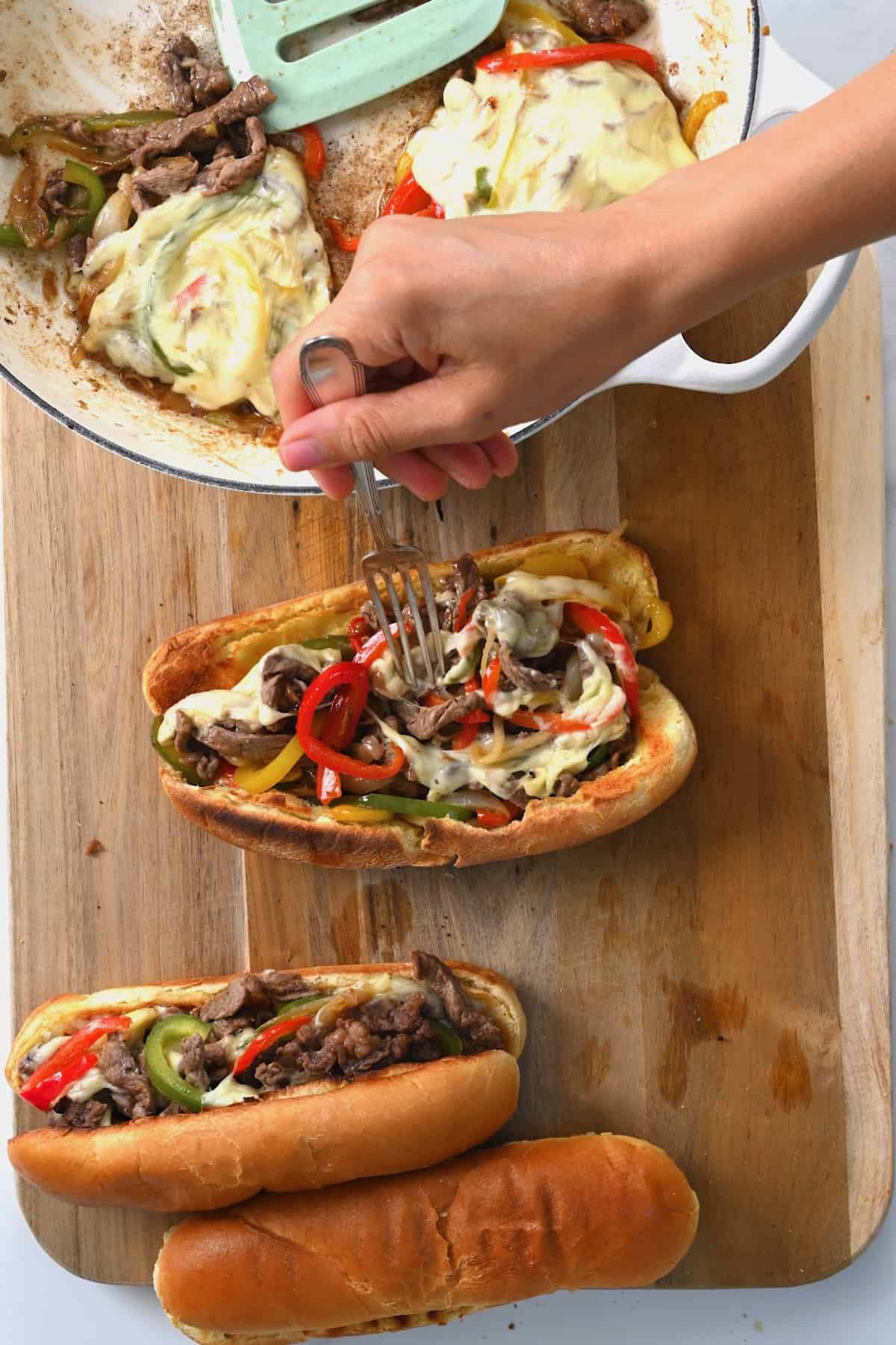 Placing meat and pepper filling into long bread rolls