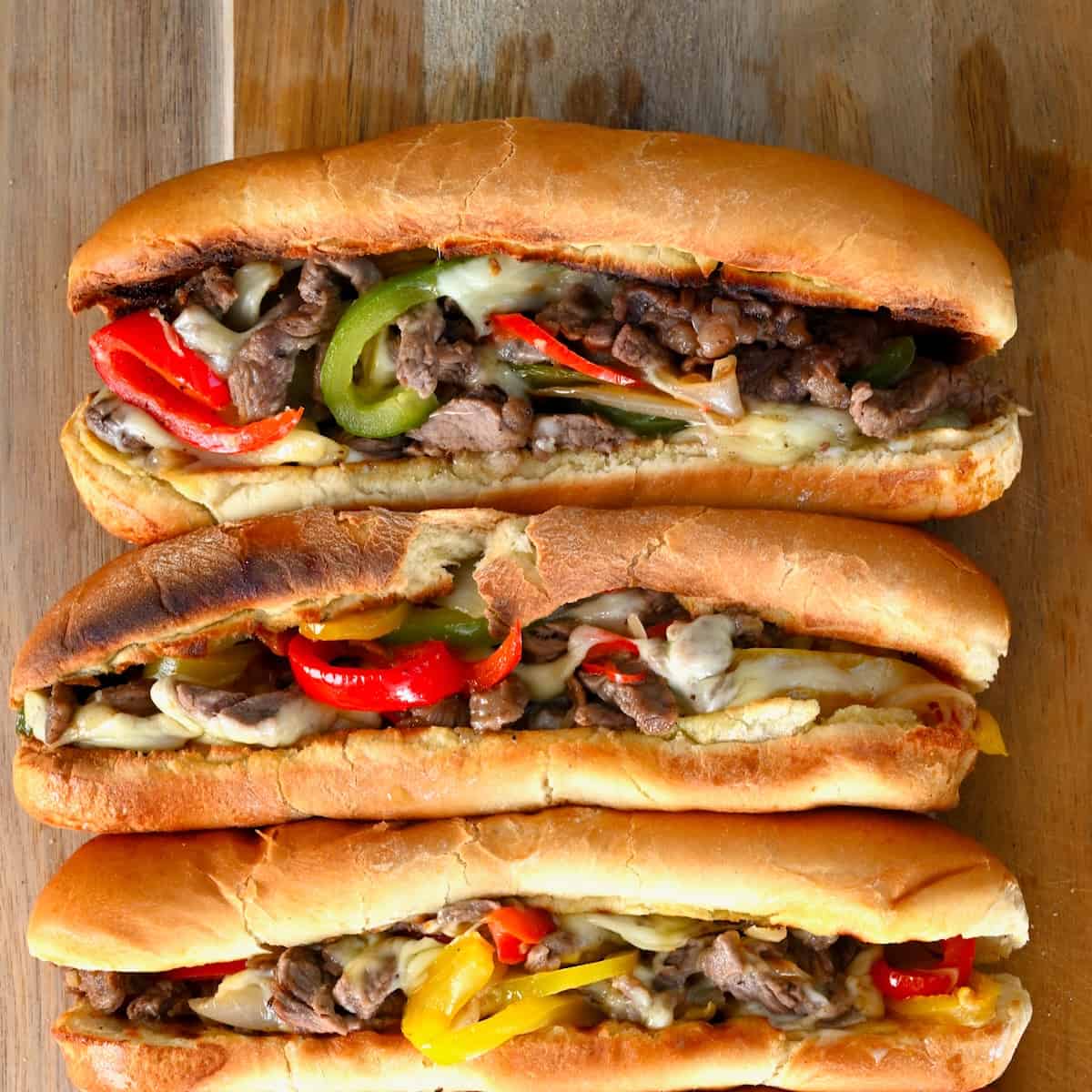 Four Philly cheesesteak sandwiches with melted cheese and peppers