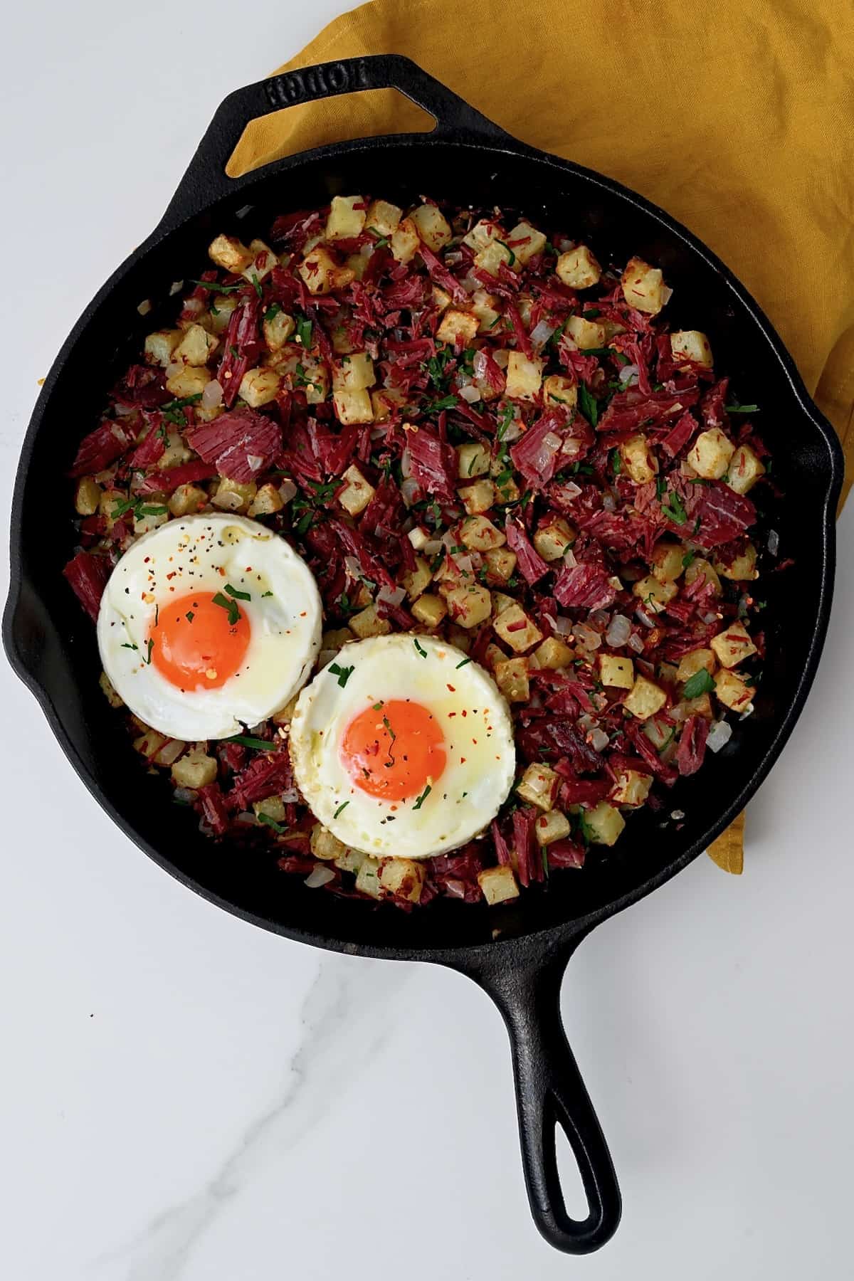A pan with corned beef hash and two fried eggs