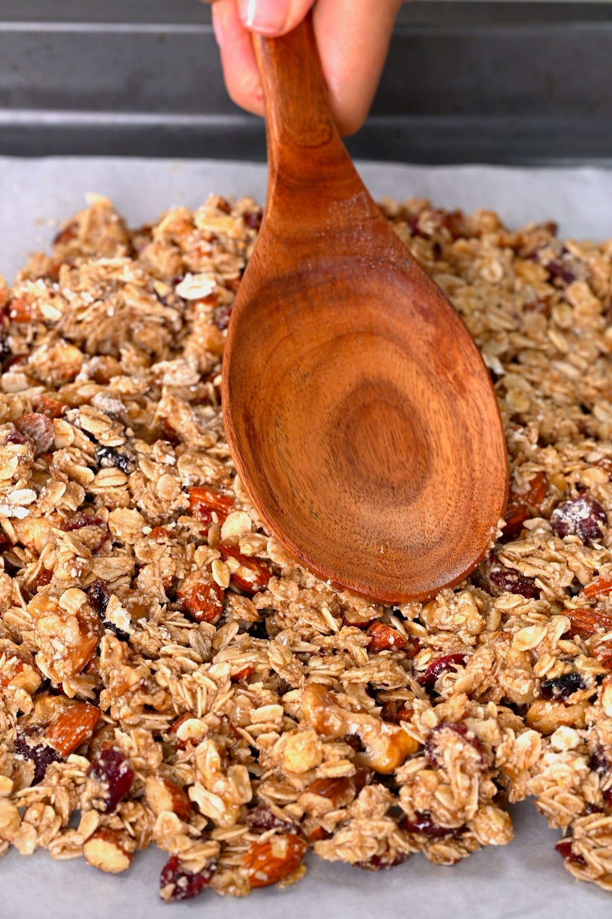 Pressing granola over a baking tray
