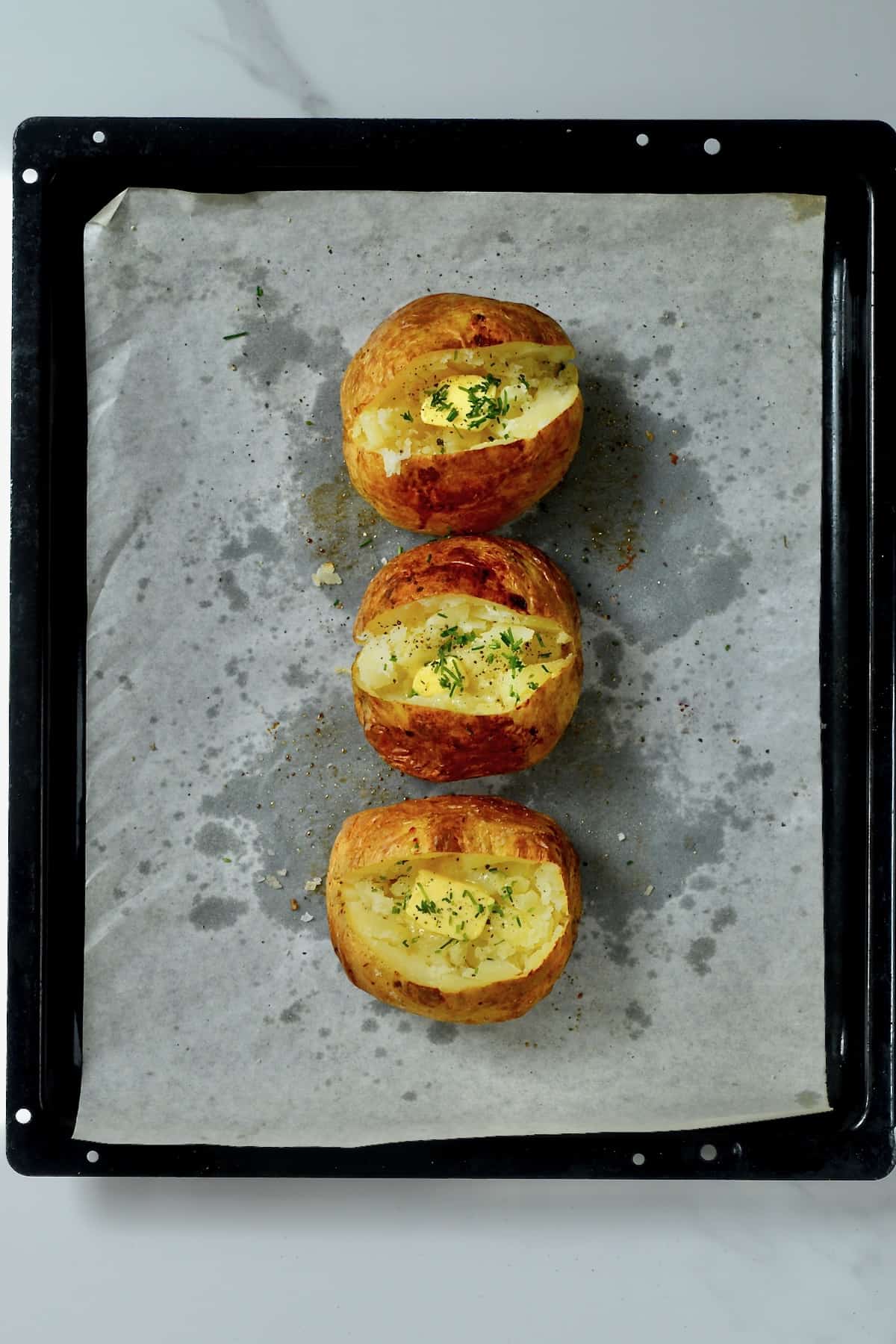 Three baked potatoes with butter and chives