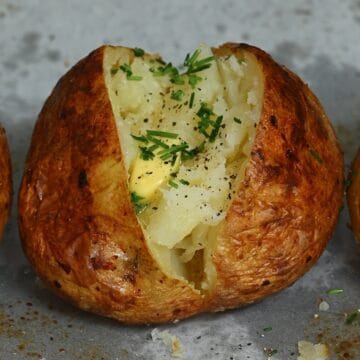 A baked potato topped with butter and chives