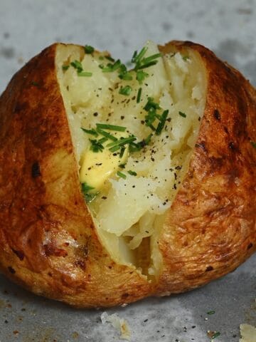 A baked potato topped with butter and chives