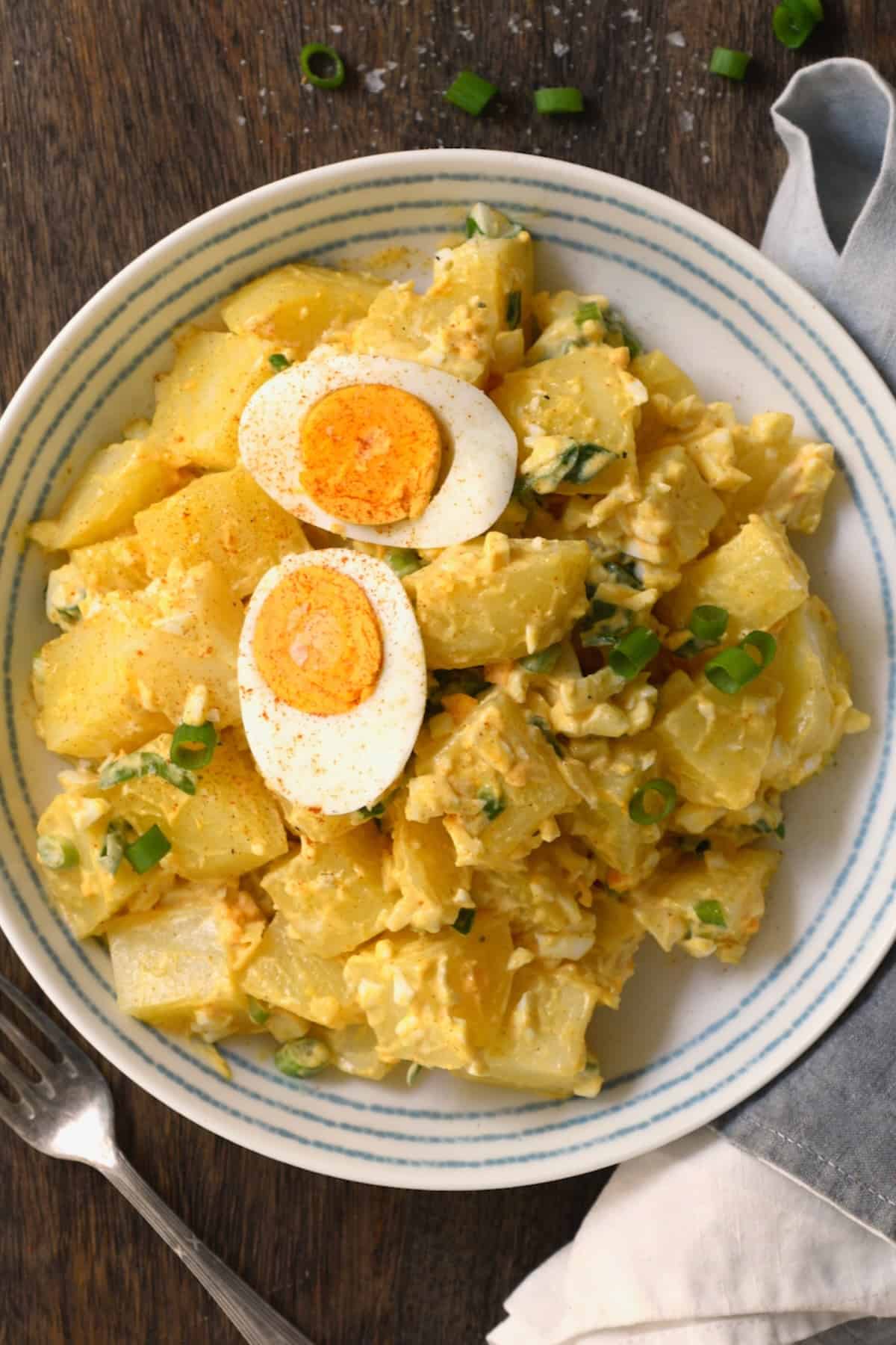 A serving of potato egg salad topped with a boiled halved egg