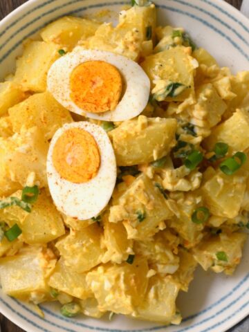 A serving of potato egg salad topped with a boiled halved egg
