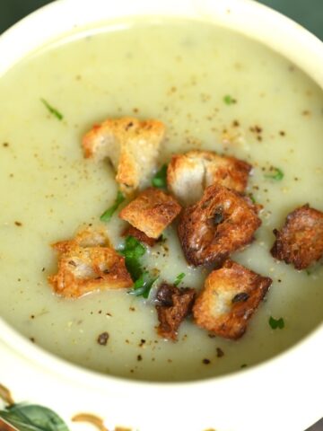 A bowl with potato leek soup with croutons on top